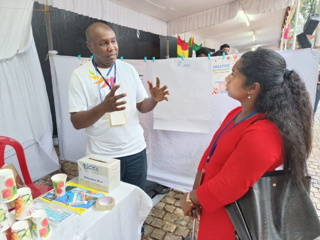 RICCA NGO Founder Kenneth, in white Tshirt explaining our approach to a stakeholder, in red dress, during exhibition in Kerala, India